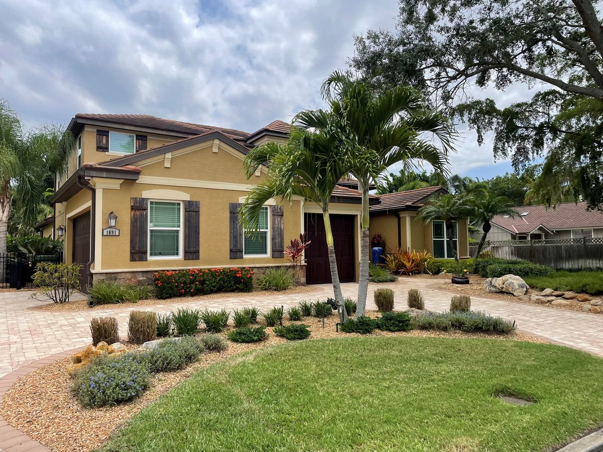 Two-storey home with layered foundation planting, curved mulch beds and a paver driveway