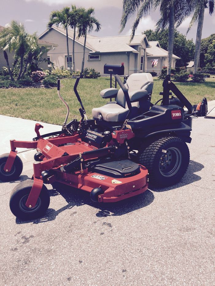 Zero-turn riding mower parked on a driveway at the start of a service visit