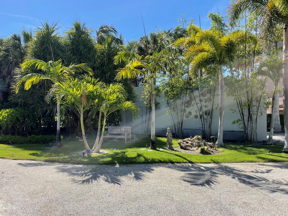 Palm grove and gravel drive with garden statuary and an irrigation zone running