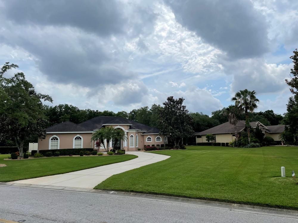 Wide stripe-mowed front lawn and curved driveway at a single-storey Florida home
